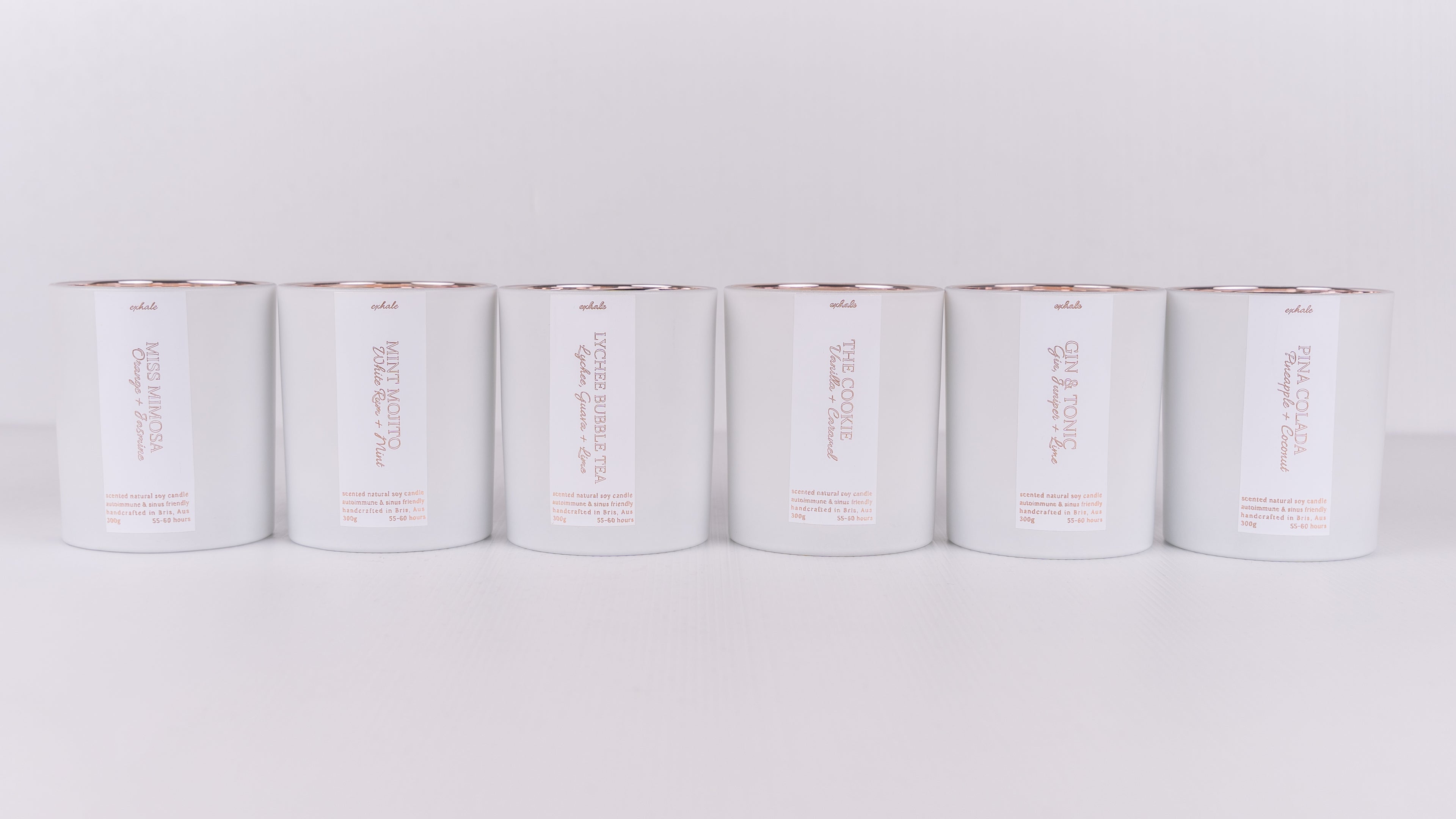 Row of white candle containers with rose gold labels
